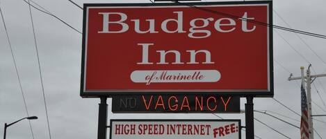 Placa de motel exibindo em destaque 'Budget Inn of Marinette' e 'SEM VAGAS'.