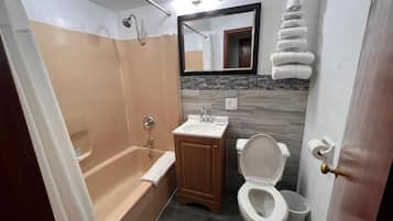 Un baño con bañera, lavamanos, inodoro y espejo.