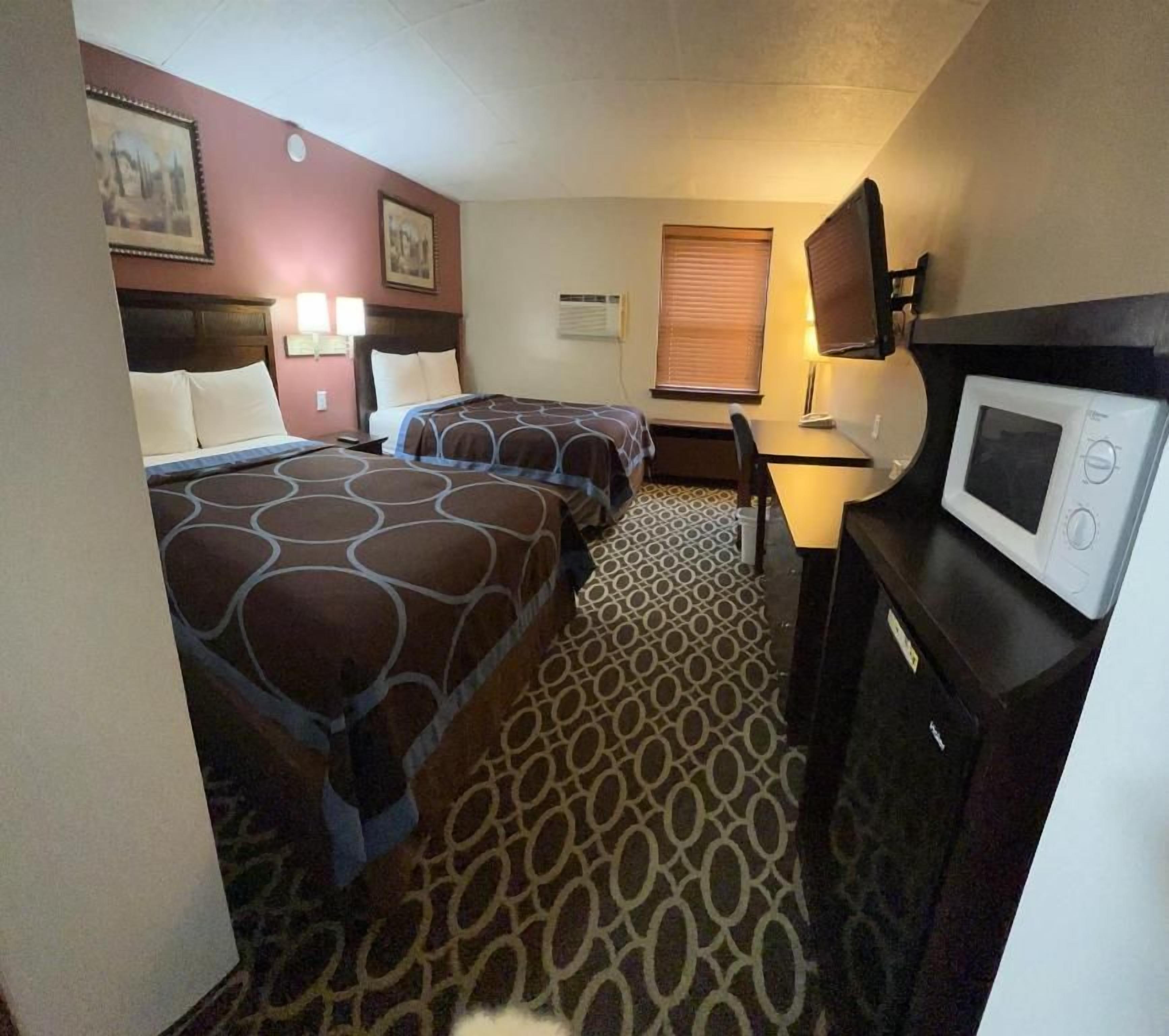 Habitación de hotel con dos camas, un escritorio, una silla, microondas y televisión.