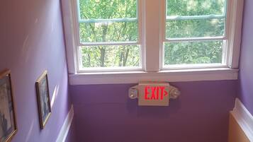A narrow stairway leading to an upper floor, with a ceiling fan and two windows providing natural light.