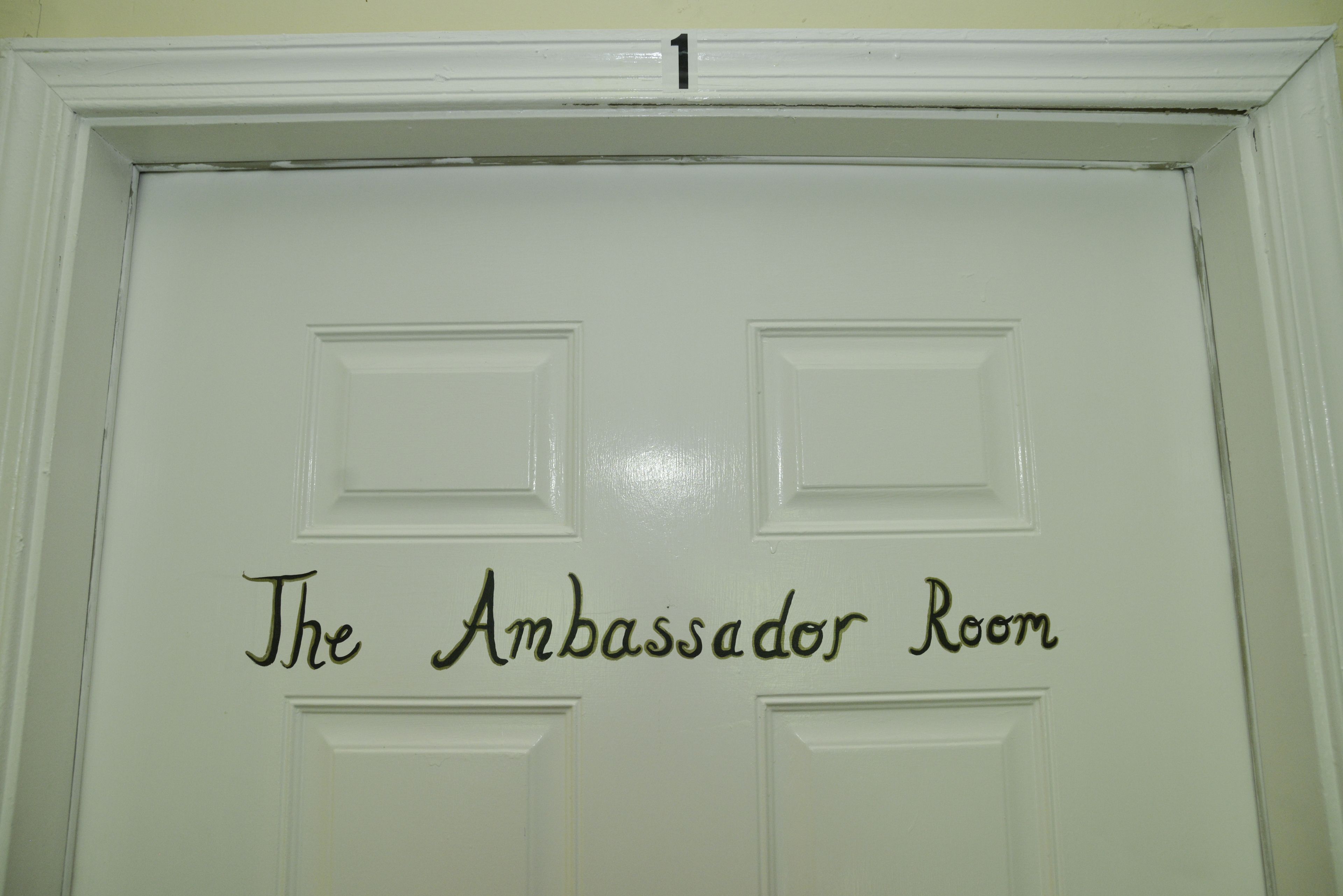 A door with the text "The Ambassador Room" and a number "1" above it.