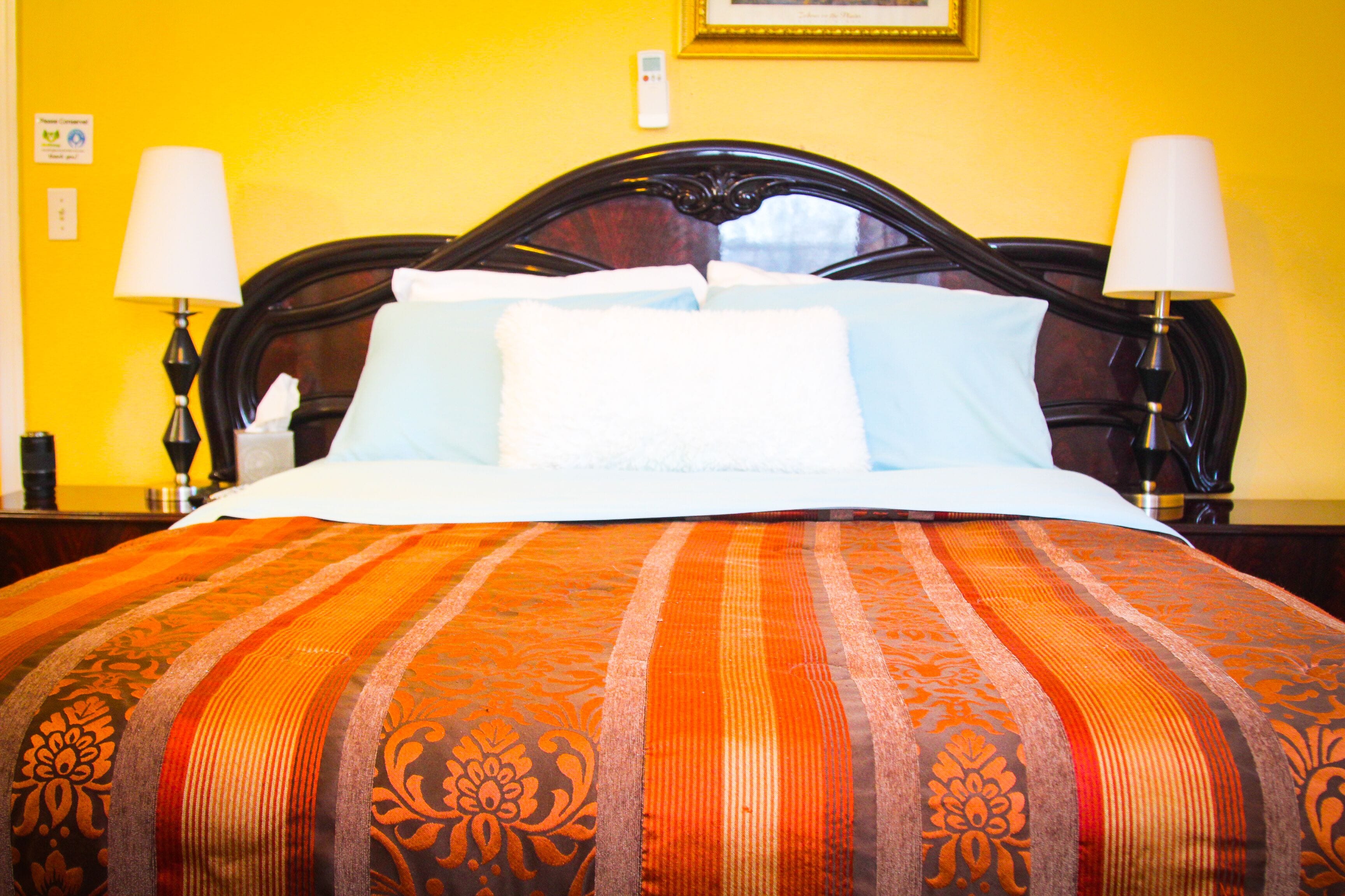 A neatly made bed with a striped bedspread, two bedside lamps, and a wooden headboard.