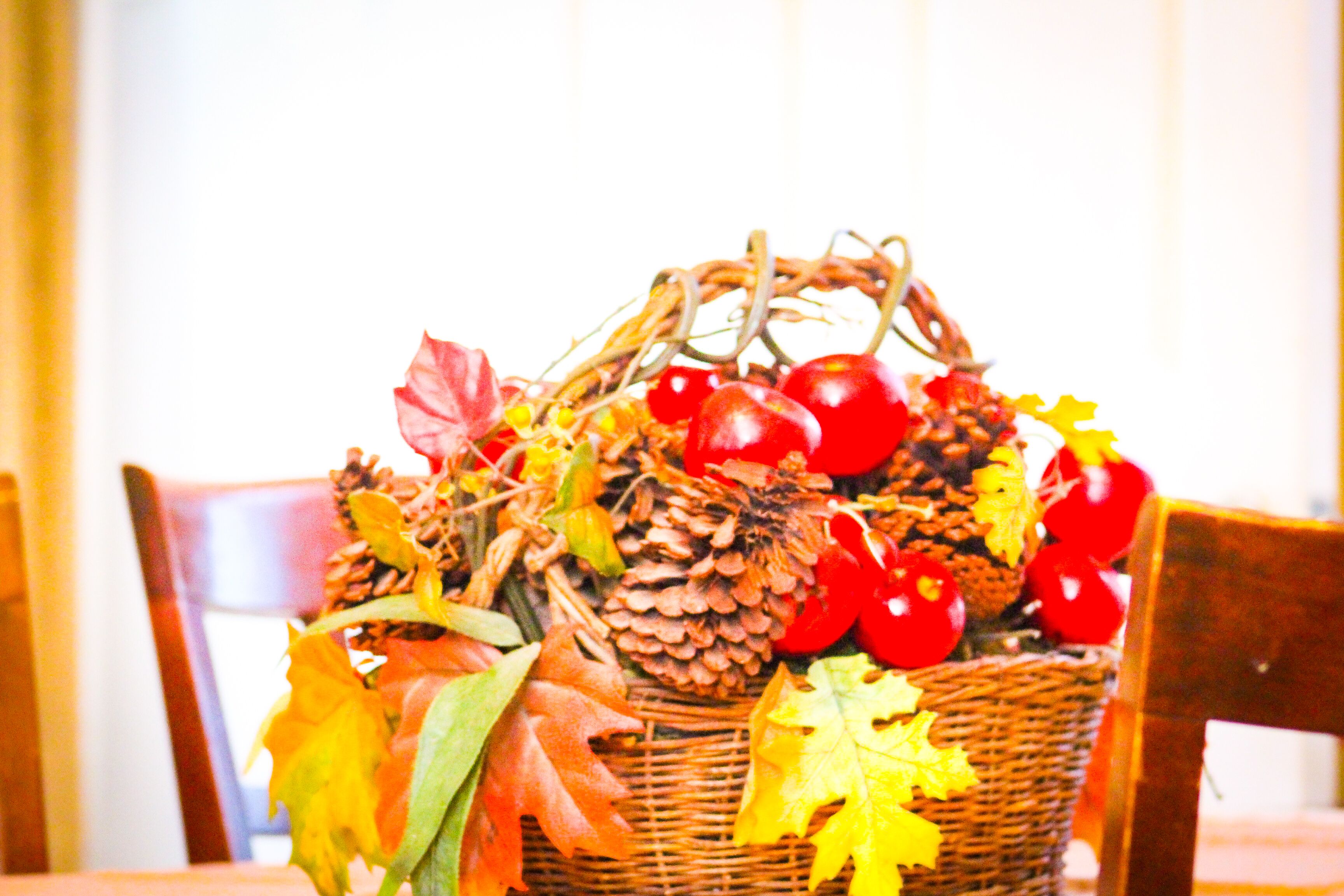 A wicker basket filled with pinecones, red berries, and autumn leaves.