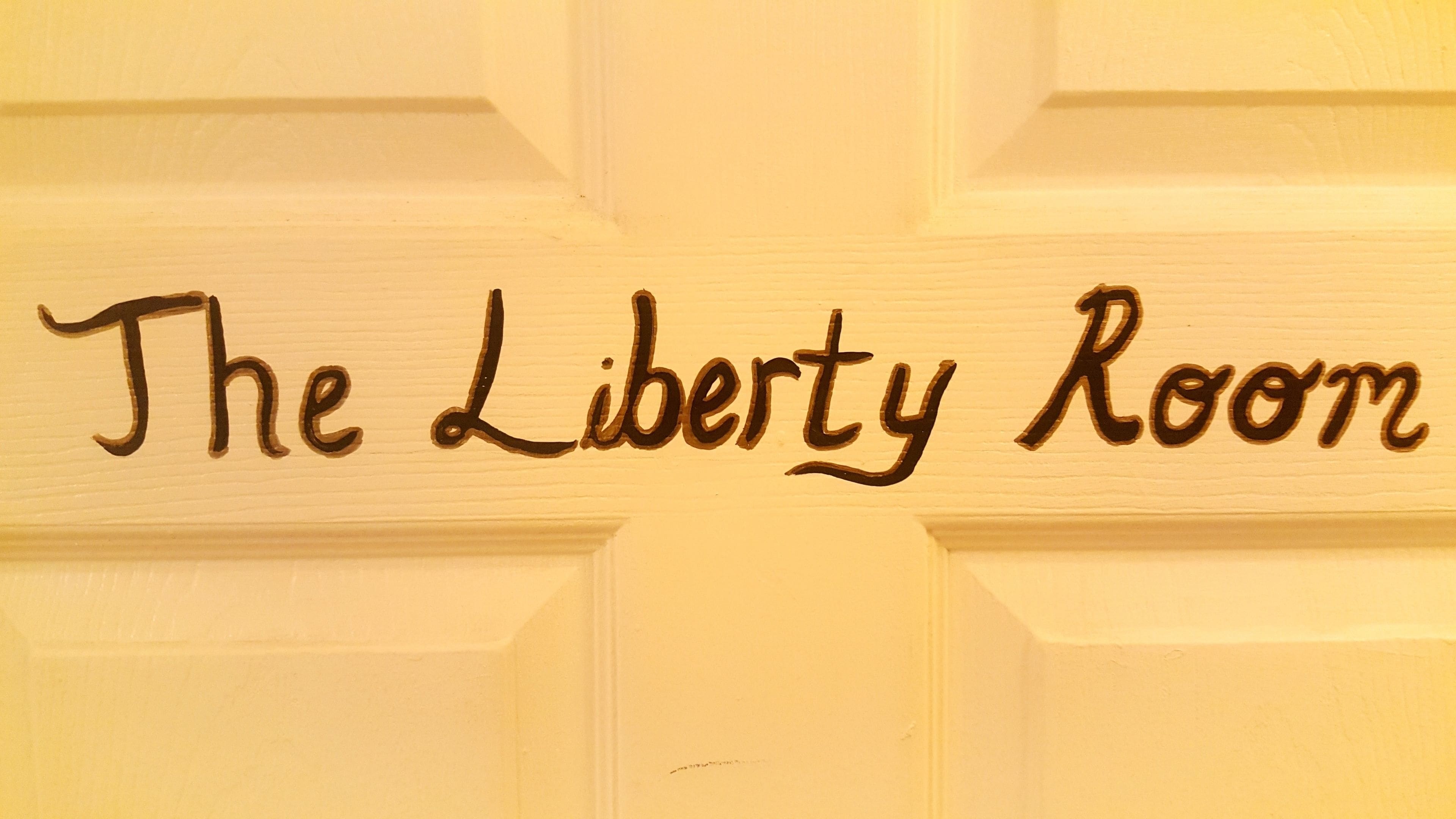 Una puerta con el texto "The Liberty Room" grabado en ella.