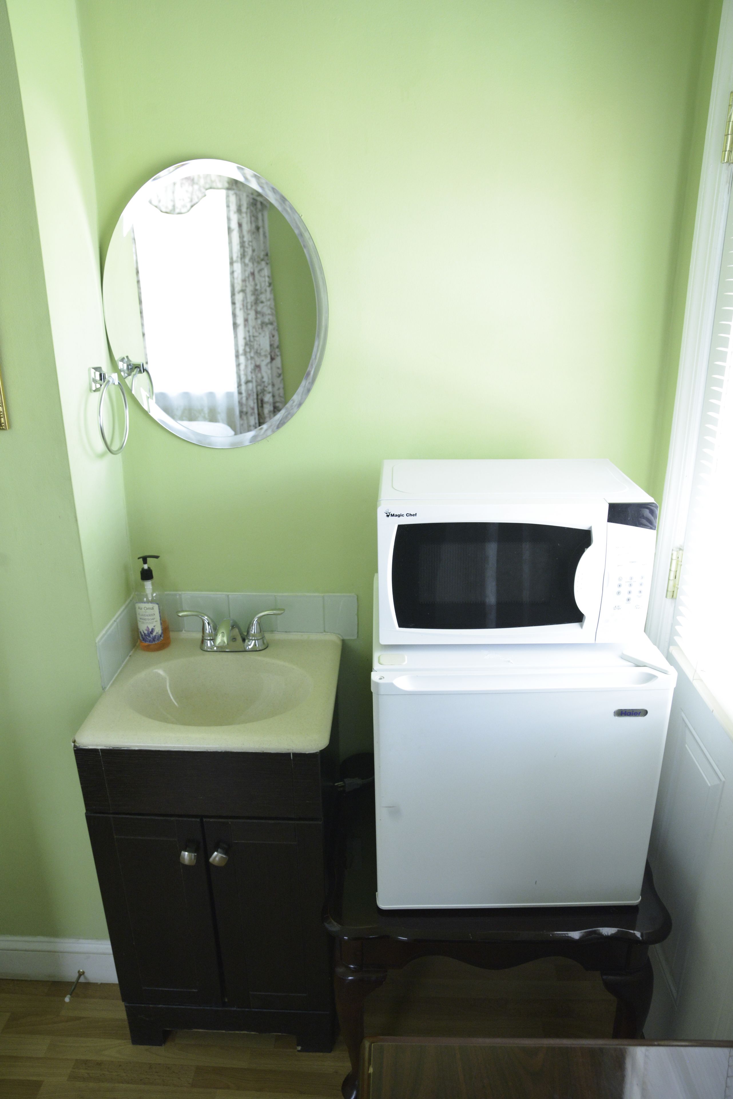 Een badkamer met een wastafel, spiegel en een magnetron.