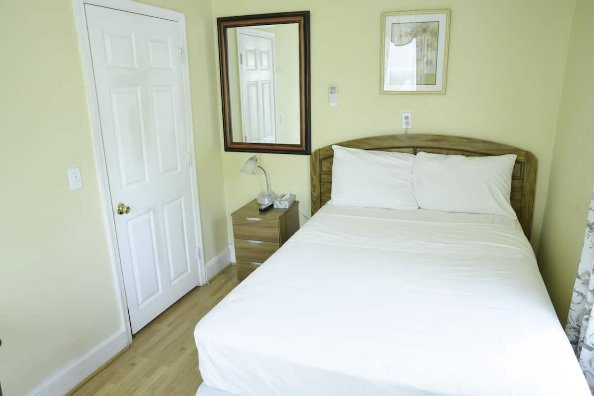 Une chambre d’hôtel avec un lit, une table de chevet, un miroir et une porte.