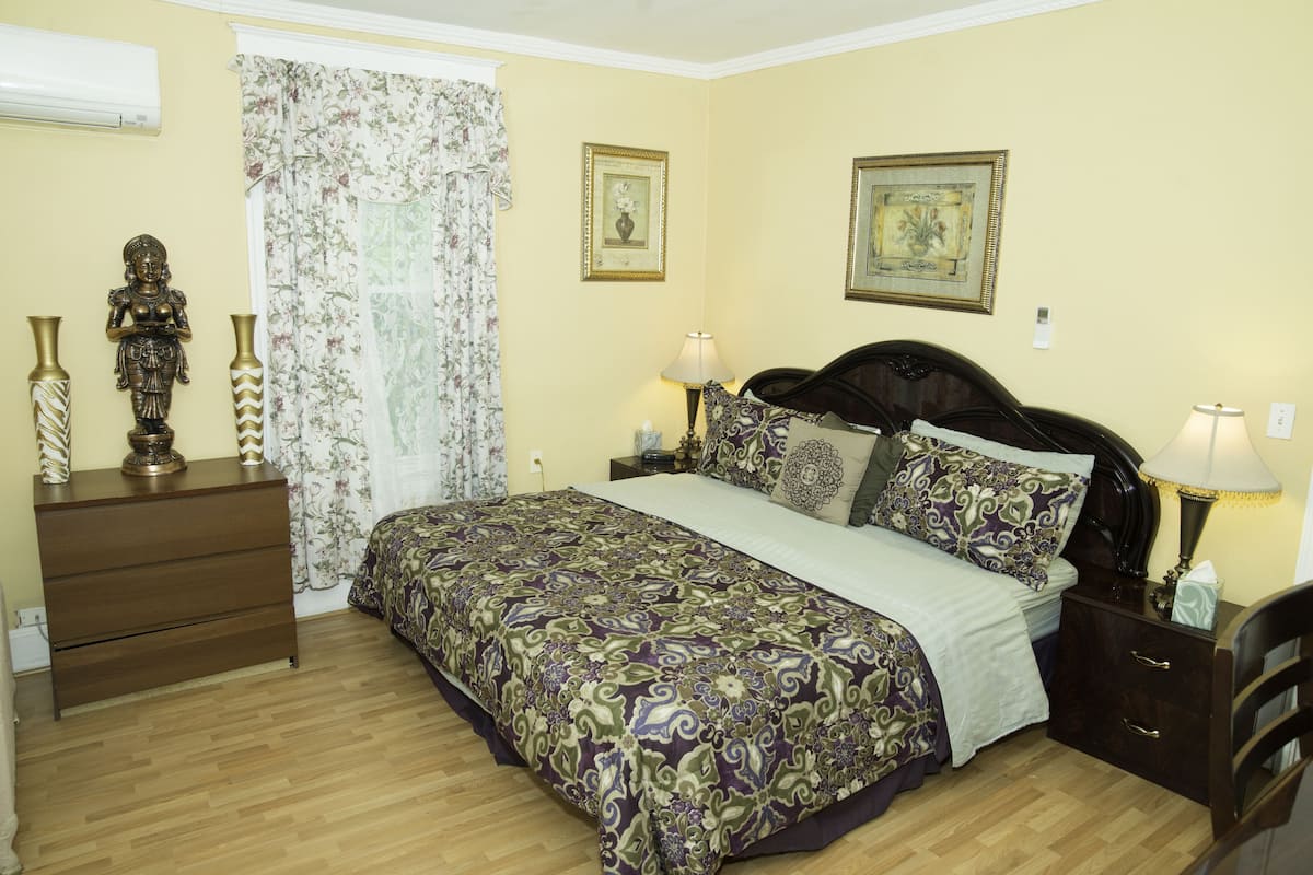 Une chambre à coucher comprenant un lit, deux tables de chevet, une commode et deux lampes fixées au mur.