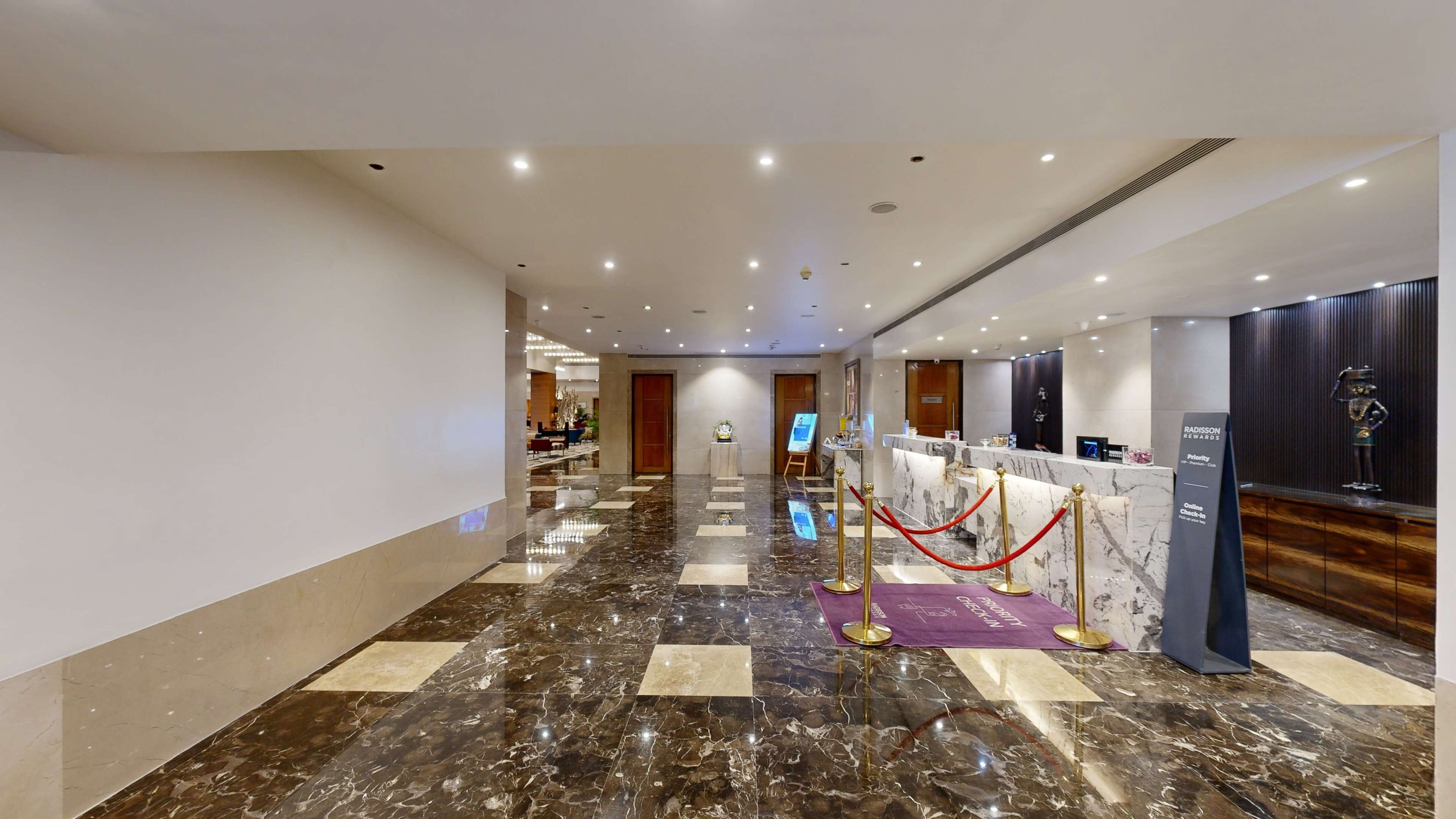 A hotel lobby with a marble floor, a reception desk, and a statue.