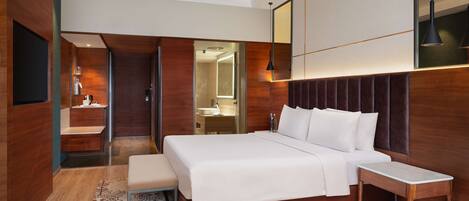 A modern hotel room with a large bed, bedside table, and a mirror above the bed.