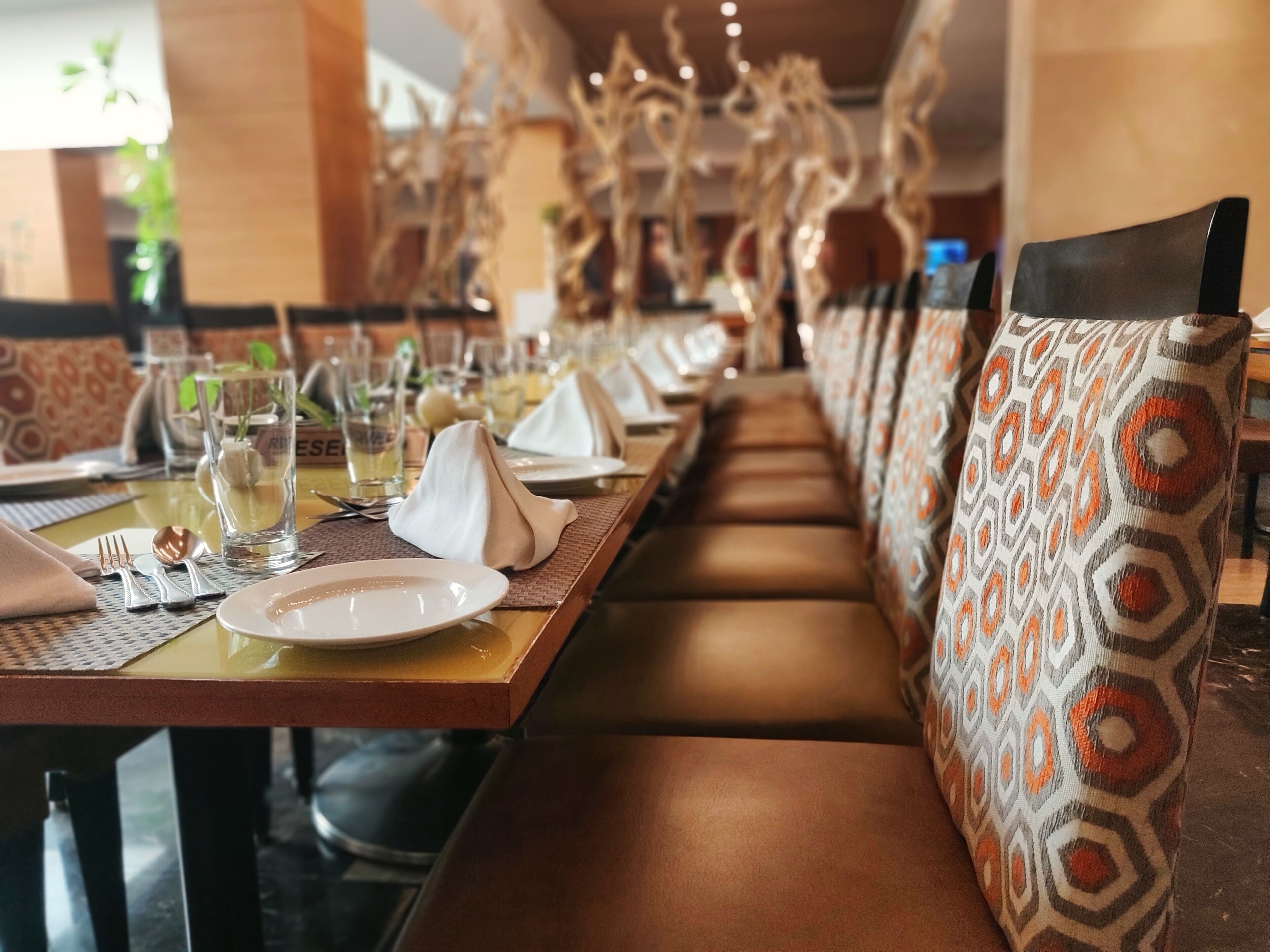 A restaurant with long tables, cushioned benches, and decorative wall art.