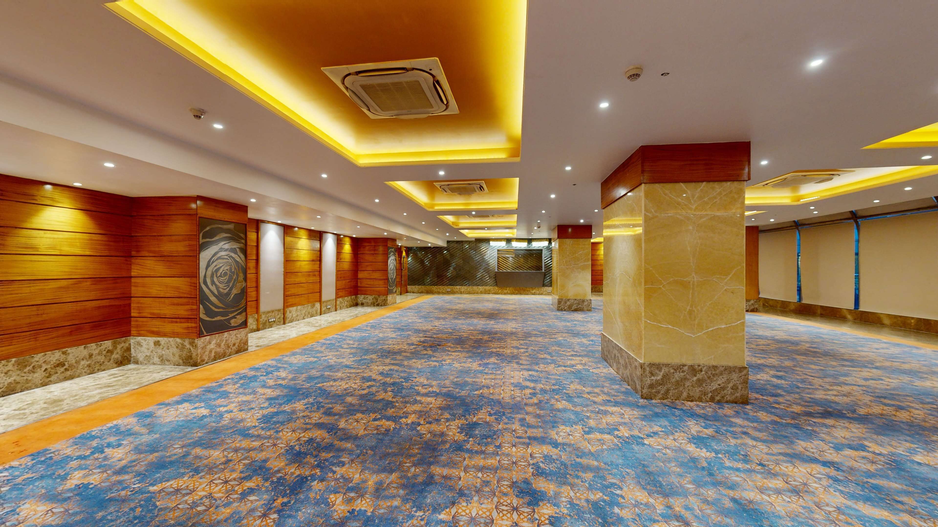 Un amplio salón con alfombra estampada, paneles de madera y un pilar central.