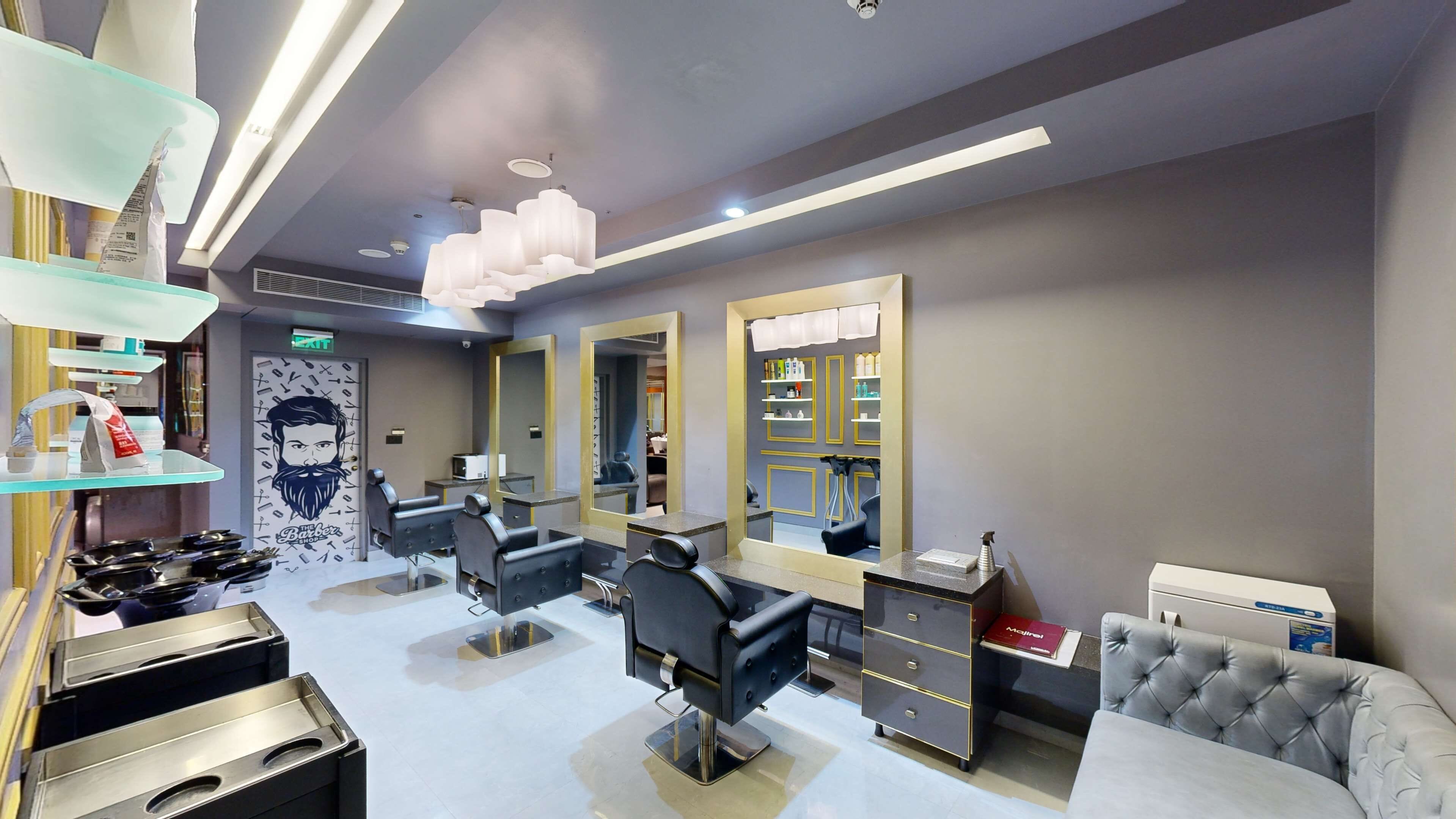 Een moderne kapsalon met drie zwarte kappersstoelen, een grote spiegel en planken met haarproducten.