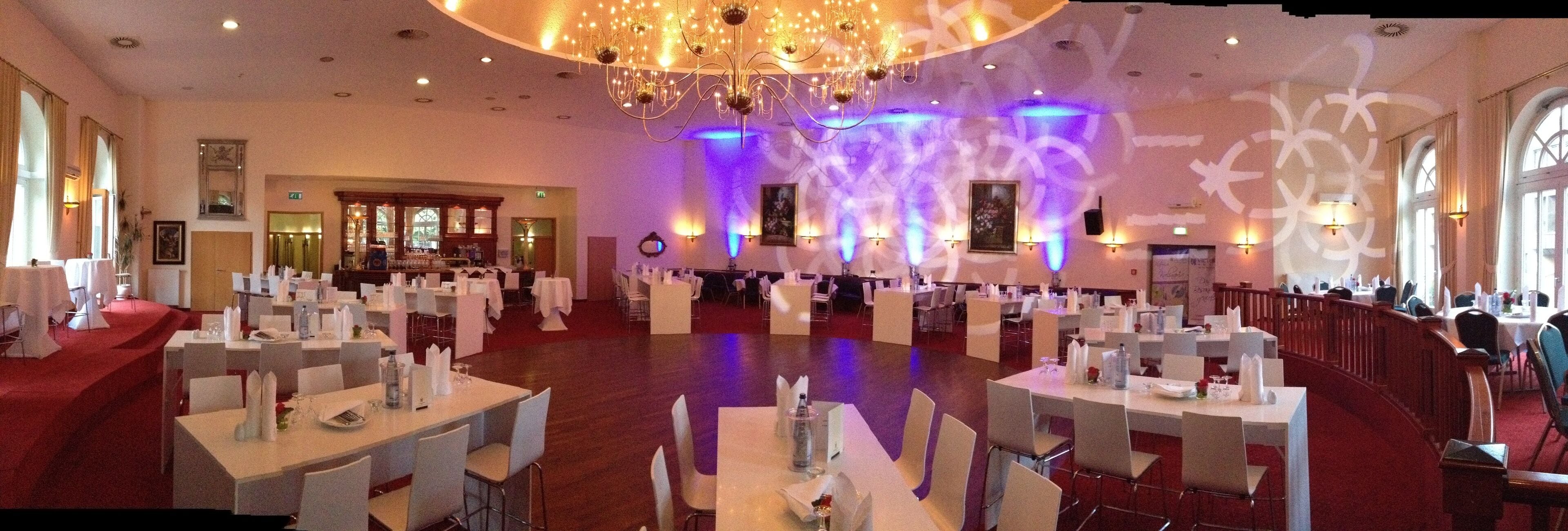Un amplio comedor con múltiples mesas y sillas, un candelabro y luces en las paredes.