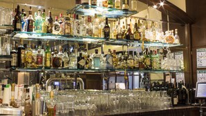 Una zona de bar con varias estanterías llenas de botellas de licores y una variedad de vasos.