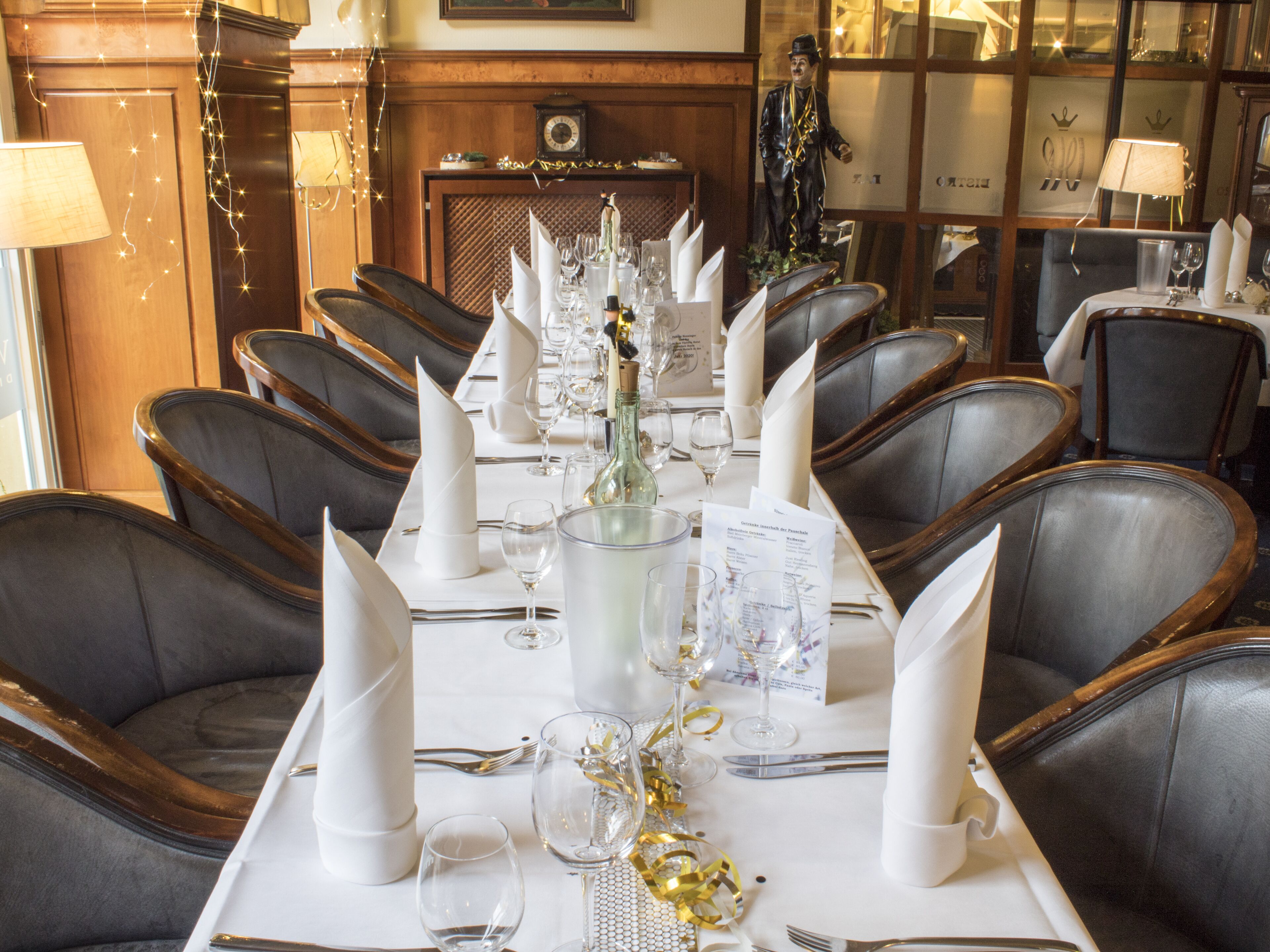 Ein formeller Speisesaal mit einem langen Tisch, der für eine Mahlzeit gedeckt ist, umgeben von Ledersesseln.
