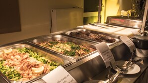 Un bufé con diversos platos, incluyendo mariscos, vegetales y un guiso de carne.