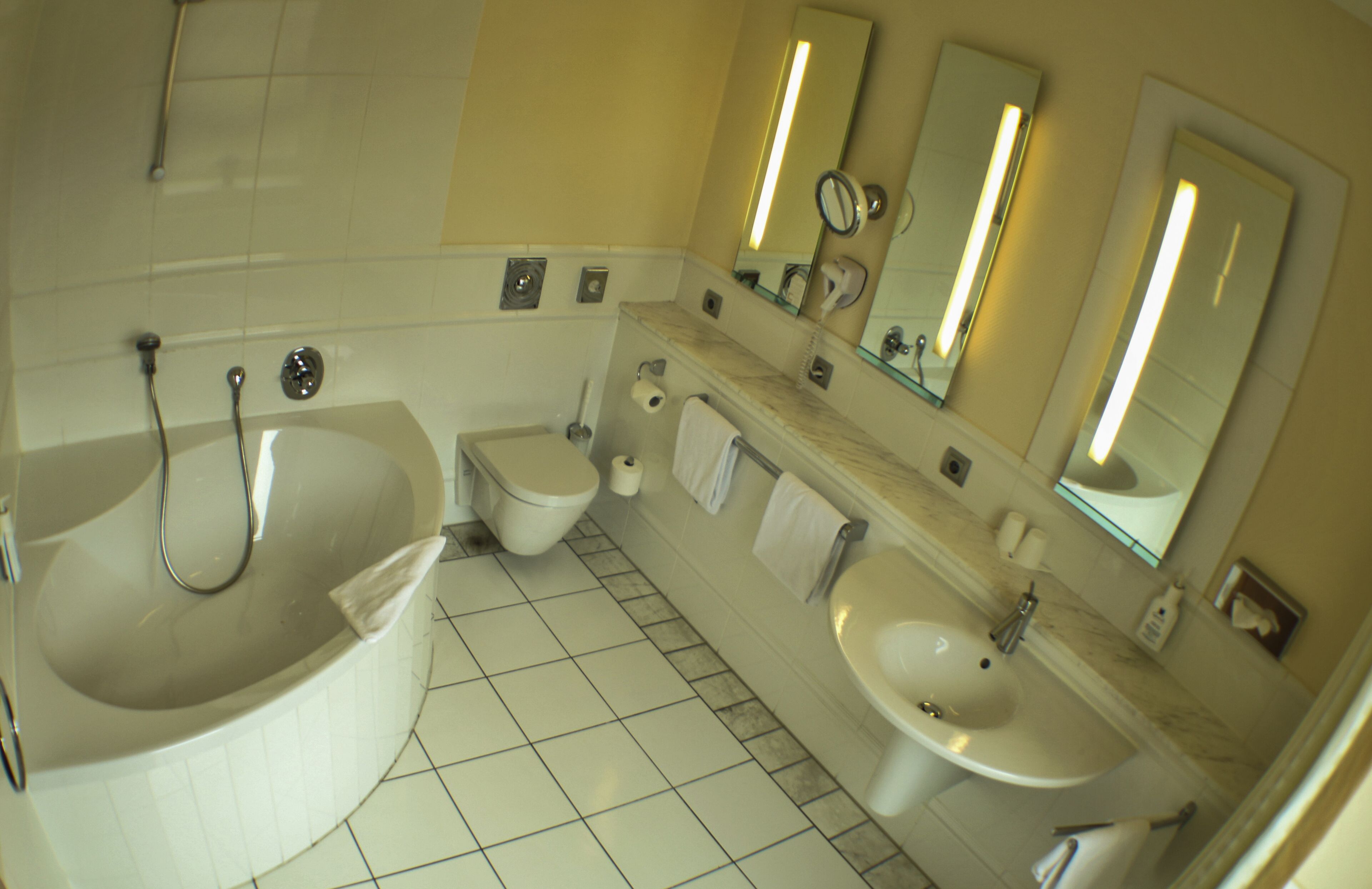 Un baño con bañera, inodoro, lavamanos y espejos.