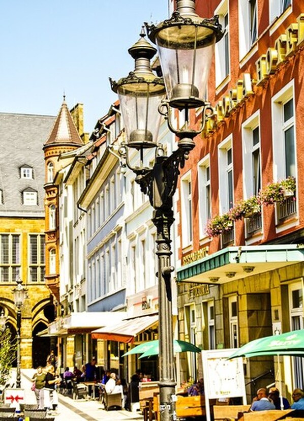 Une rue bordée de bâtiments historiques, avec des terrasses et un lampadaire.