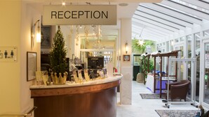 Un área de recepción con un cartel que dice "RECEPTION", un árbol de Navidad y un mostrador de recepción.