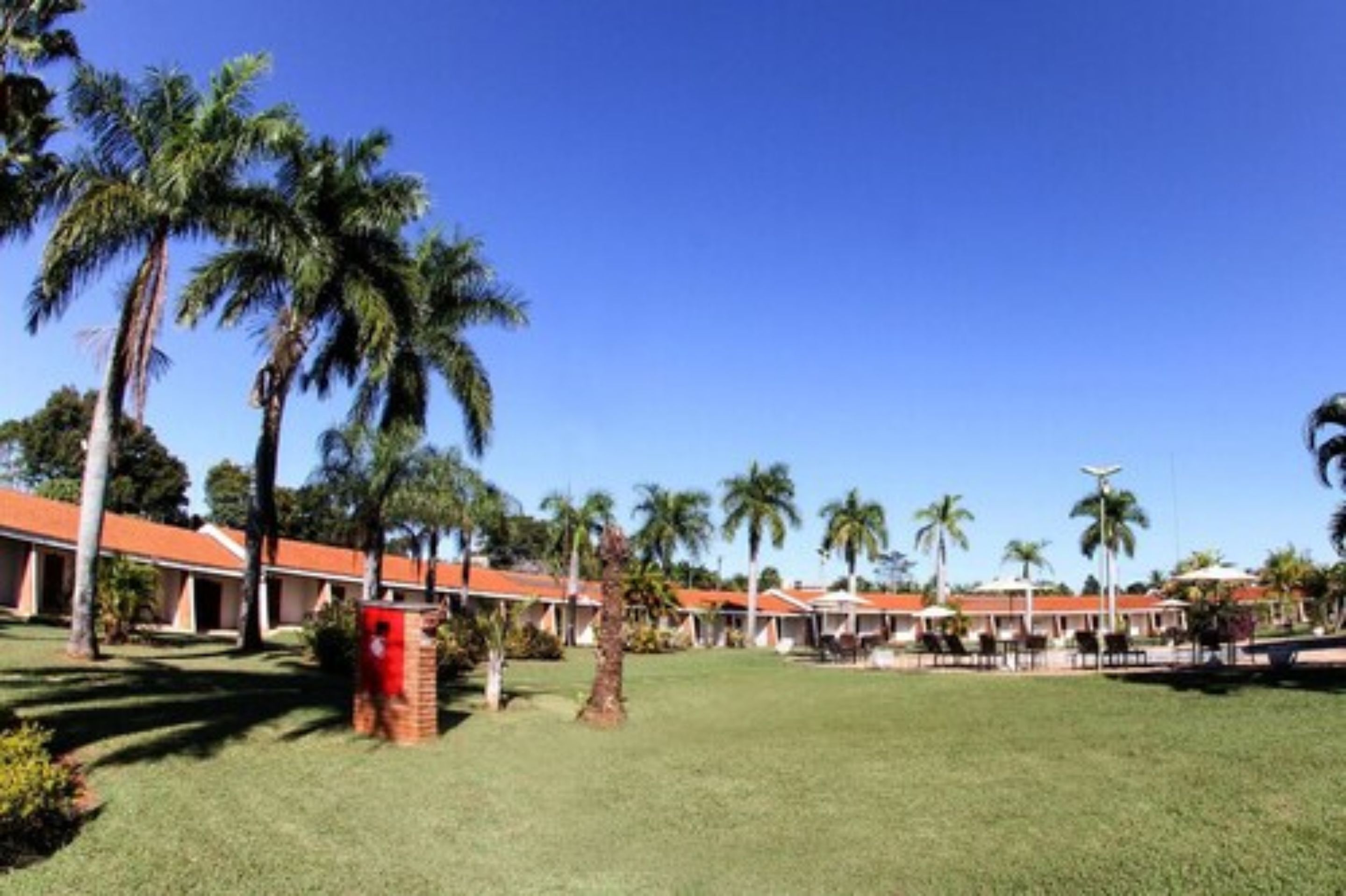 A resort with multiple bungalow-style buildings, palm trees, and a well-maintained lawn.