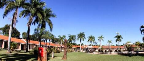 A resort with multiple bungalow-style buildings, palm trees, and a well-maintained lawn.