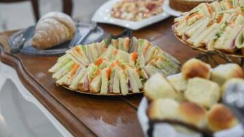 A buffet table with sandwiches, a croissant, and other pastries.