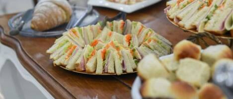 A buffet table with sandwiches, a croissant, and other pastries.