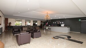 A spacious lobby with leather sofas, a reception desk, and a chandelier. - Ipê Park Hotel (São José do Rio Preto)