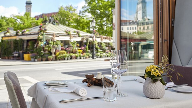 A table set for two with a view of a cityscape and a flower arrangement.