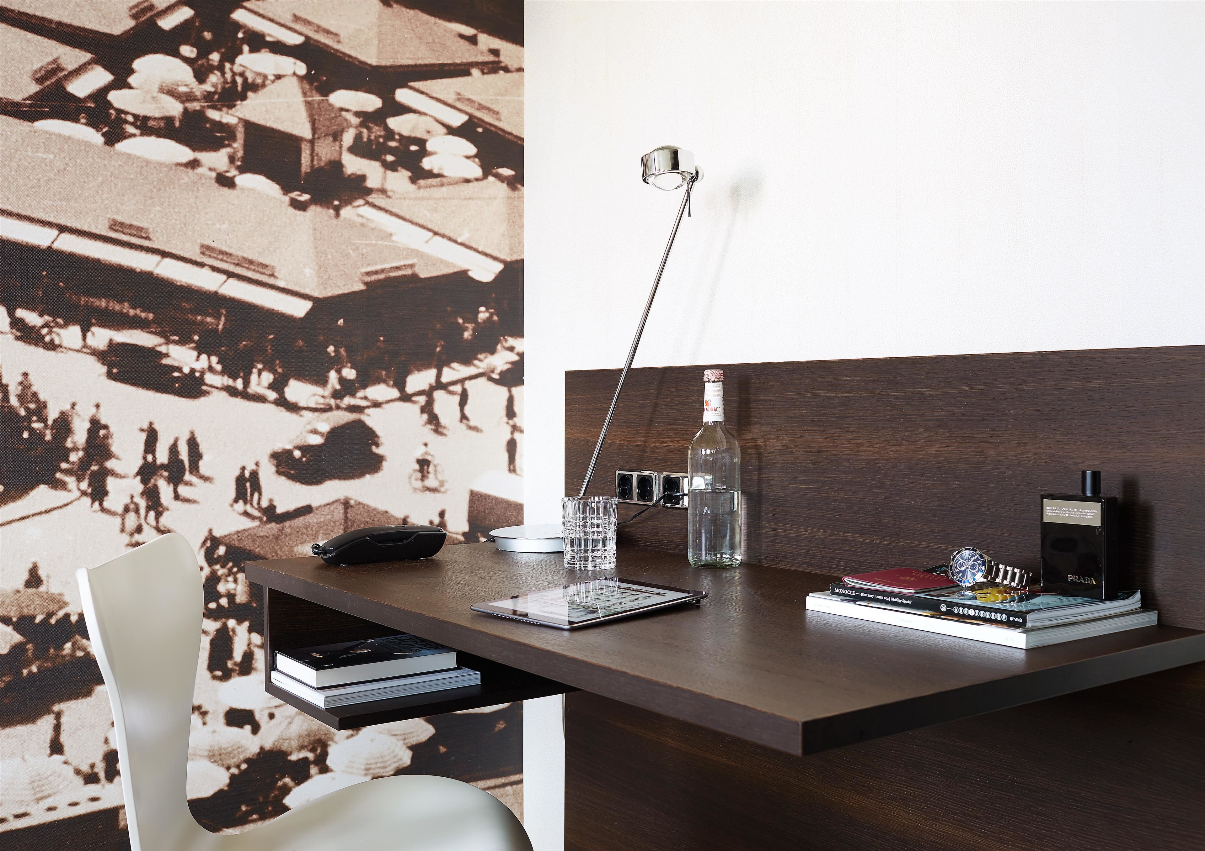 A modern desk with a laptop, books, a bottle, and a watch.