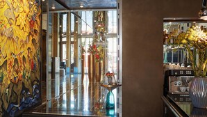 A modern lobby with a glass entrance, a coffee machine, and a large vase with flowers.