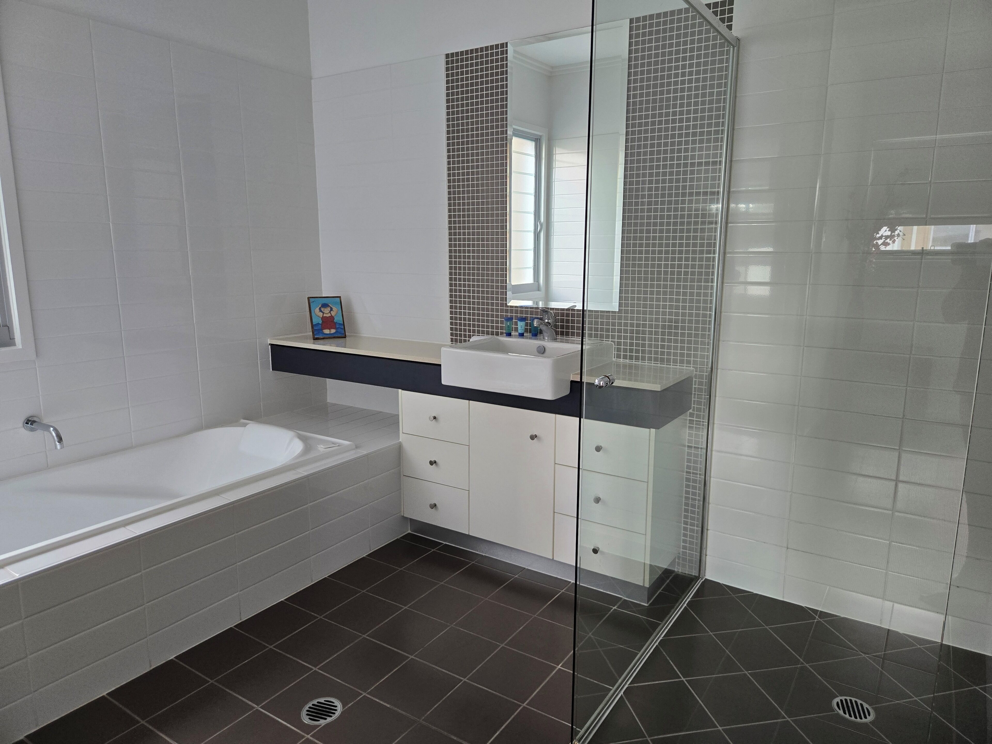 Een moderne badkamer met een bad, een wastafel met spiegel en een douchehoek.