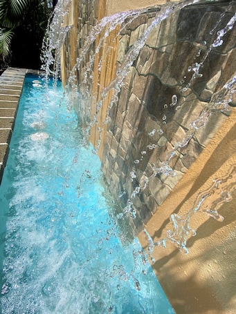 Una piscina al aire libre, sombrillas, sillones reclinables de piscina