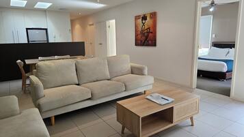 A modern living room with a sofa, coffee table, and a dining area with a table and chairs.