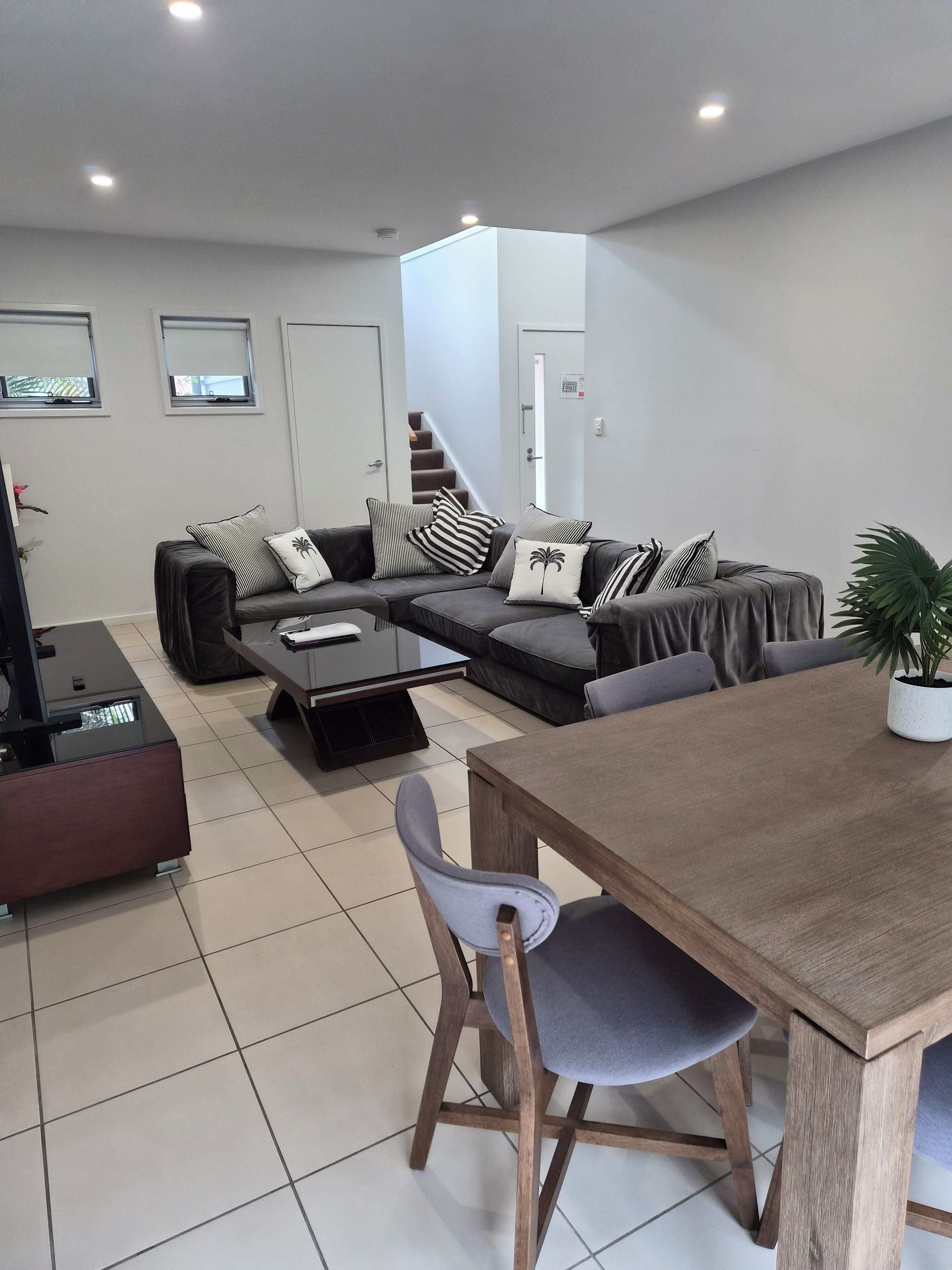 A modern living room with a grey sofa, a wooden dining table, and a grey armchair.