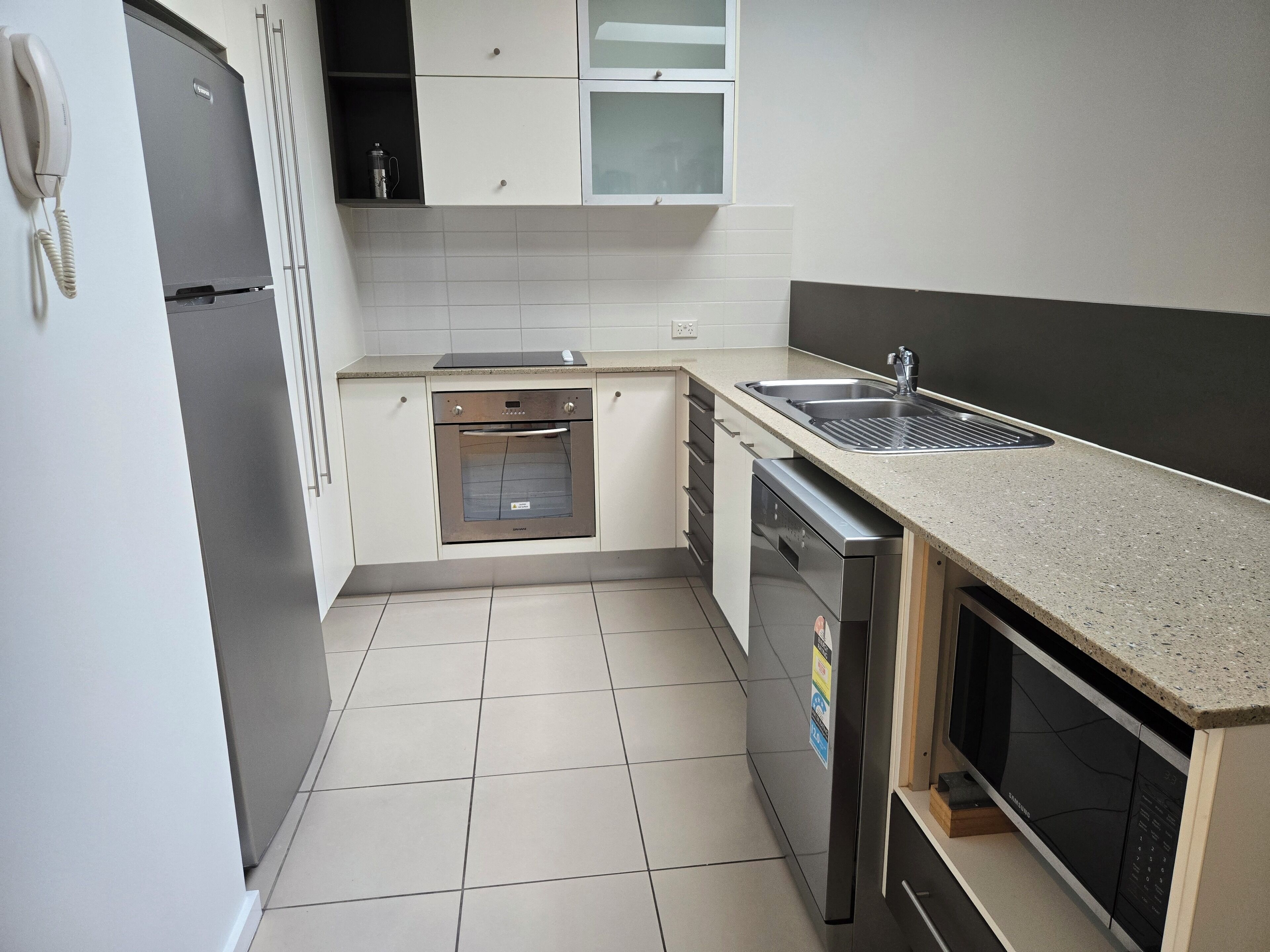 Una cocina compacta con horno integrado, lavavajillas y fregadero.