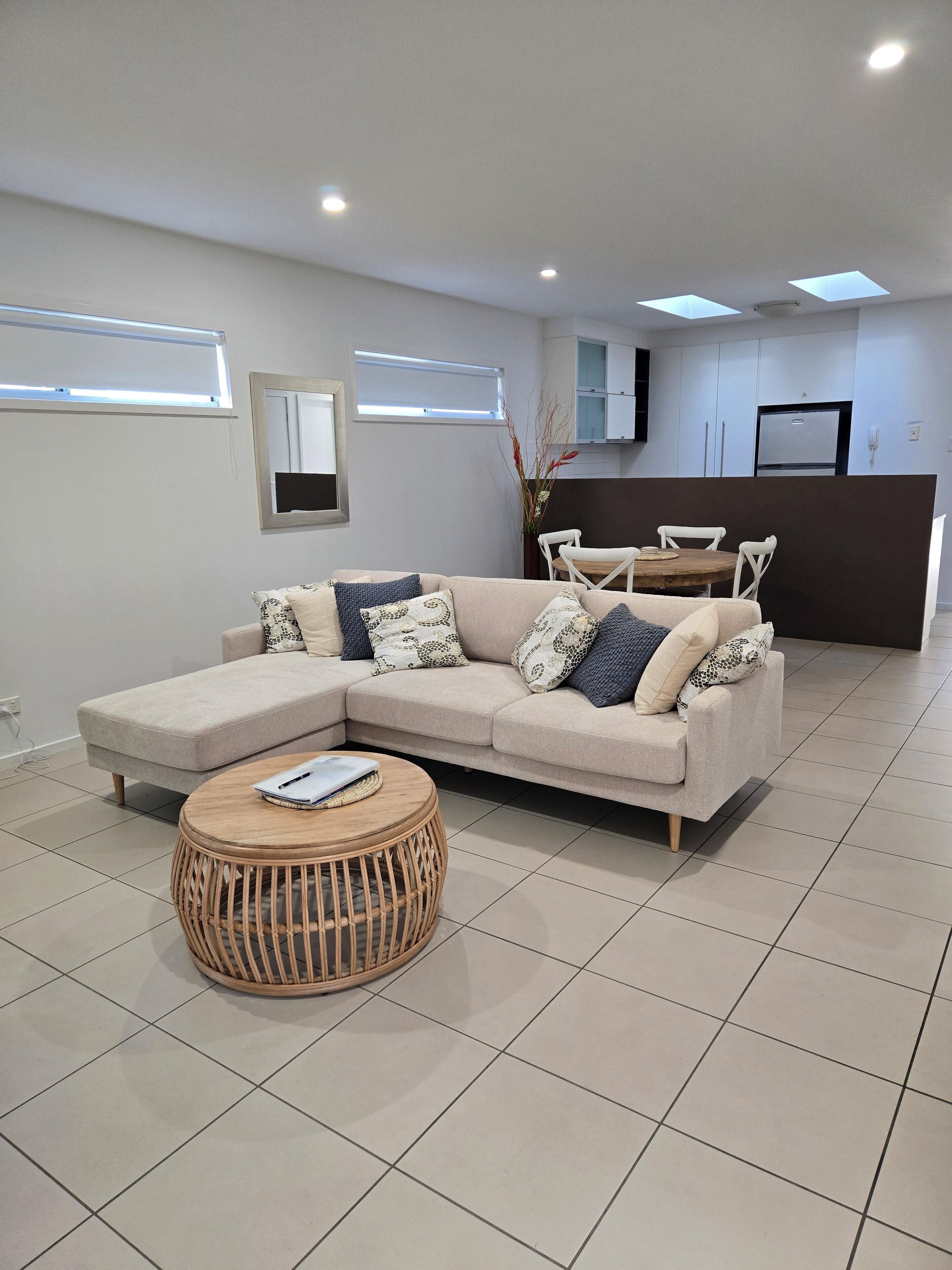 Een moderne woonkamer met een modulaire bank, een ronde salontafel en een eethoek met een kleine tafel en stoelen.