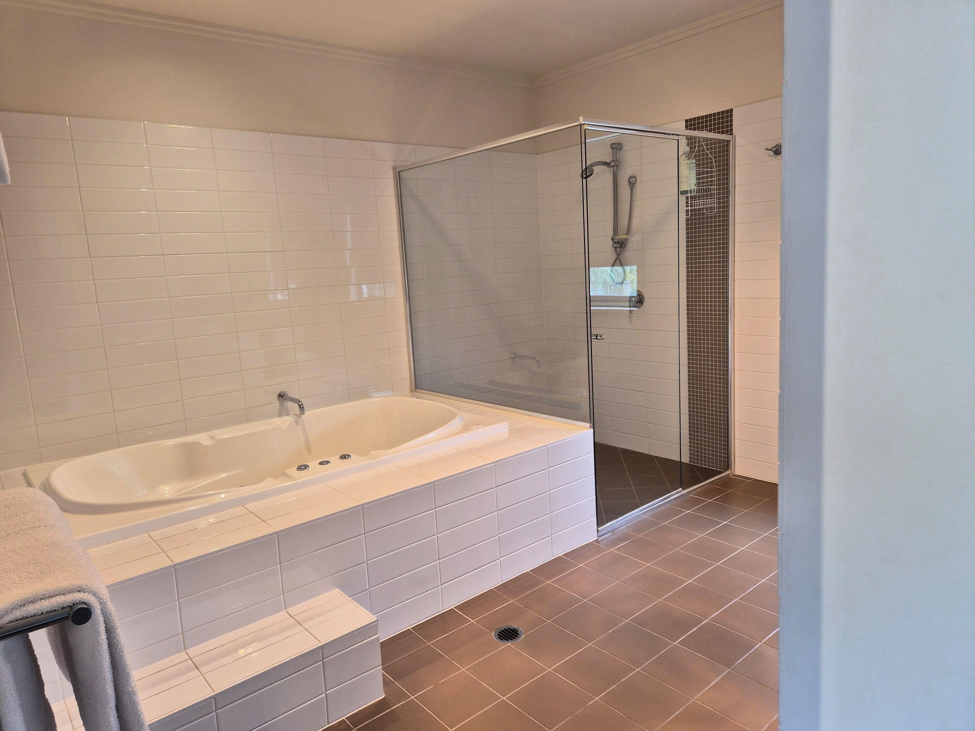 Un baño moderno con una bañera independiente, ducha con mampara de vidrio y paredes de azulejos.