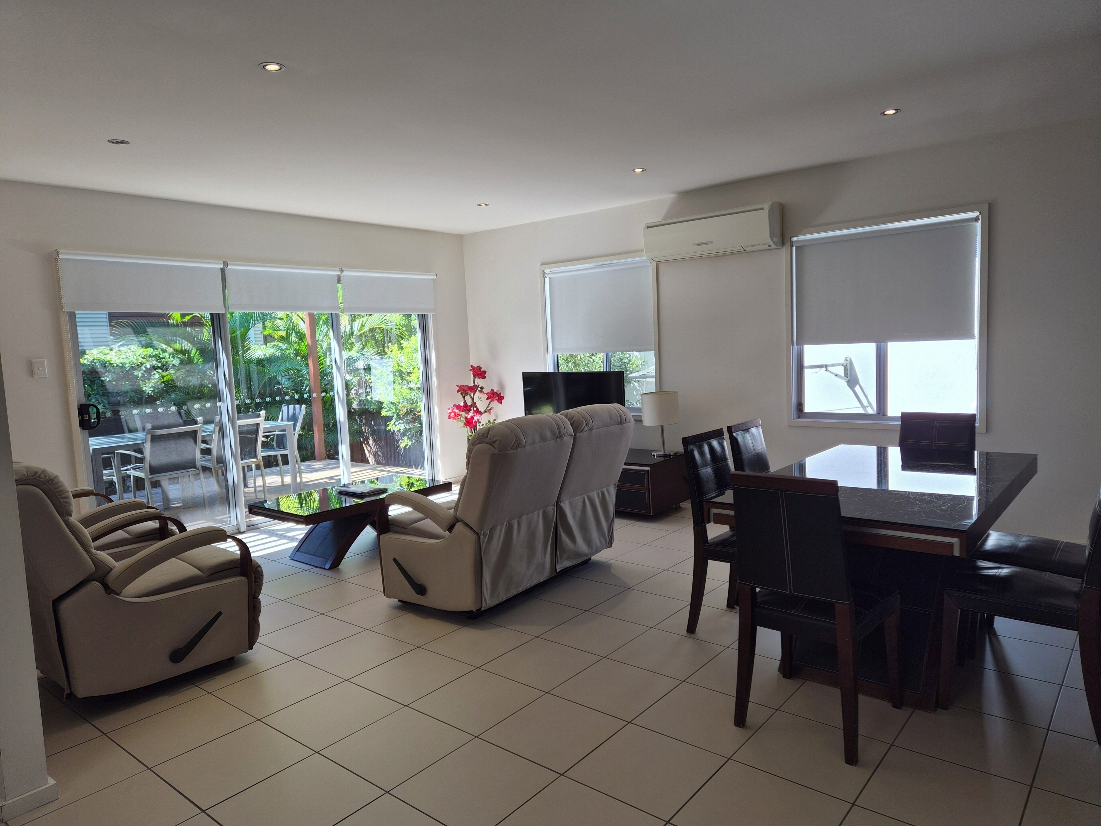 A spacious living area with a sliding glass door leading to a balcony, a dining table with chairs, and a sofa.