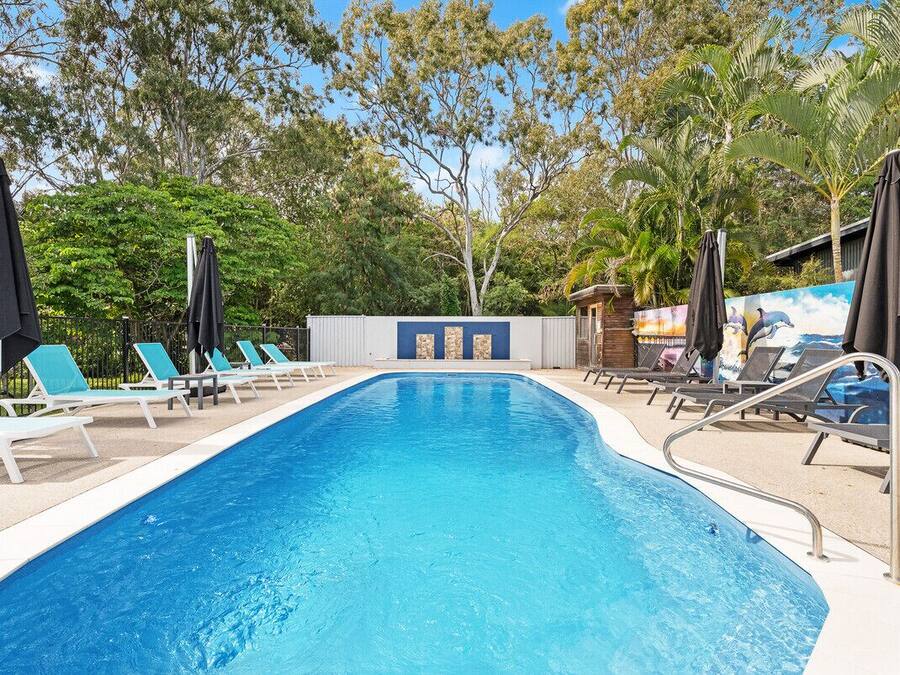 Una piscina al aire libre, sombrillas, tumbonas