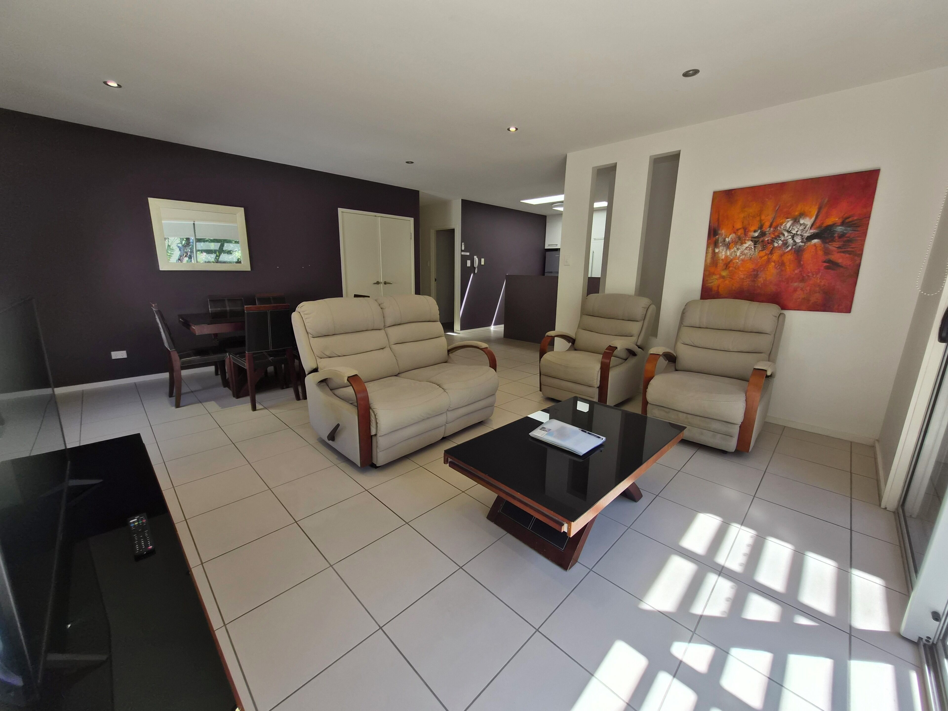 A modern living room with a sofa, armchairs, a coffee table, and a TV.