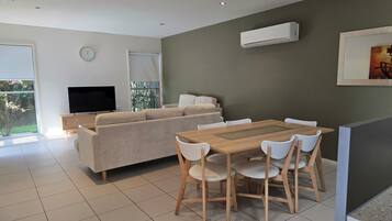 Una sala de estar moderna con sofá, televisor, mesa de comedor y sillas.
