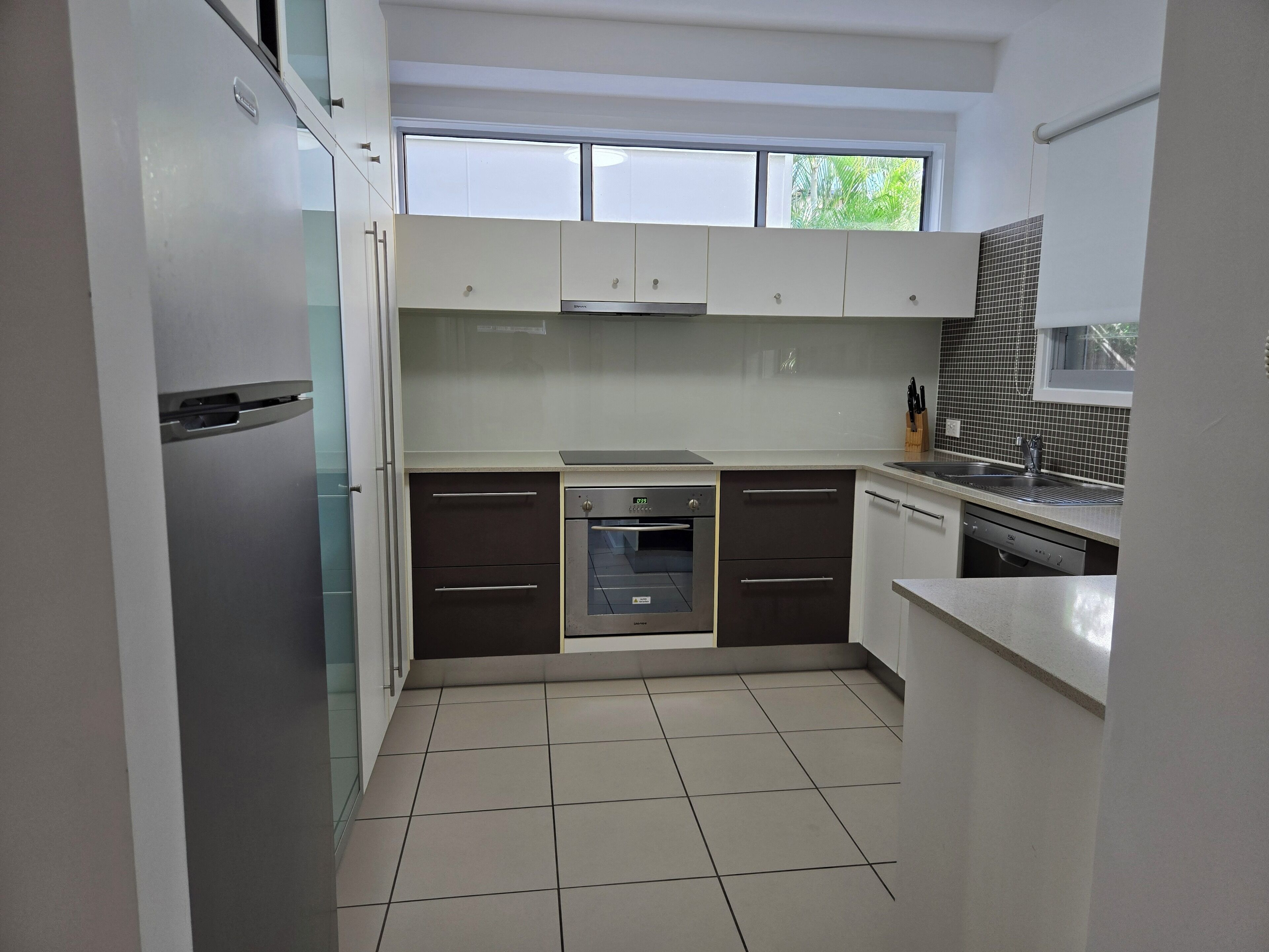 Una cocina moderna con gabinetes blancos, horno de acero inoxidable y lavavajillas.