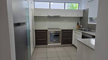 A modern kitchen with white cabinets, a stainless steel oven, and a dishwasher.