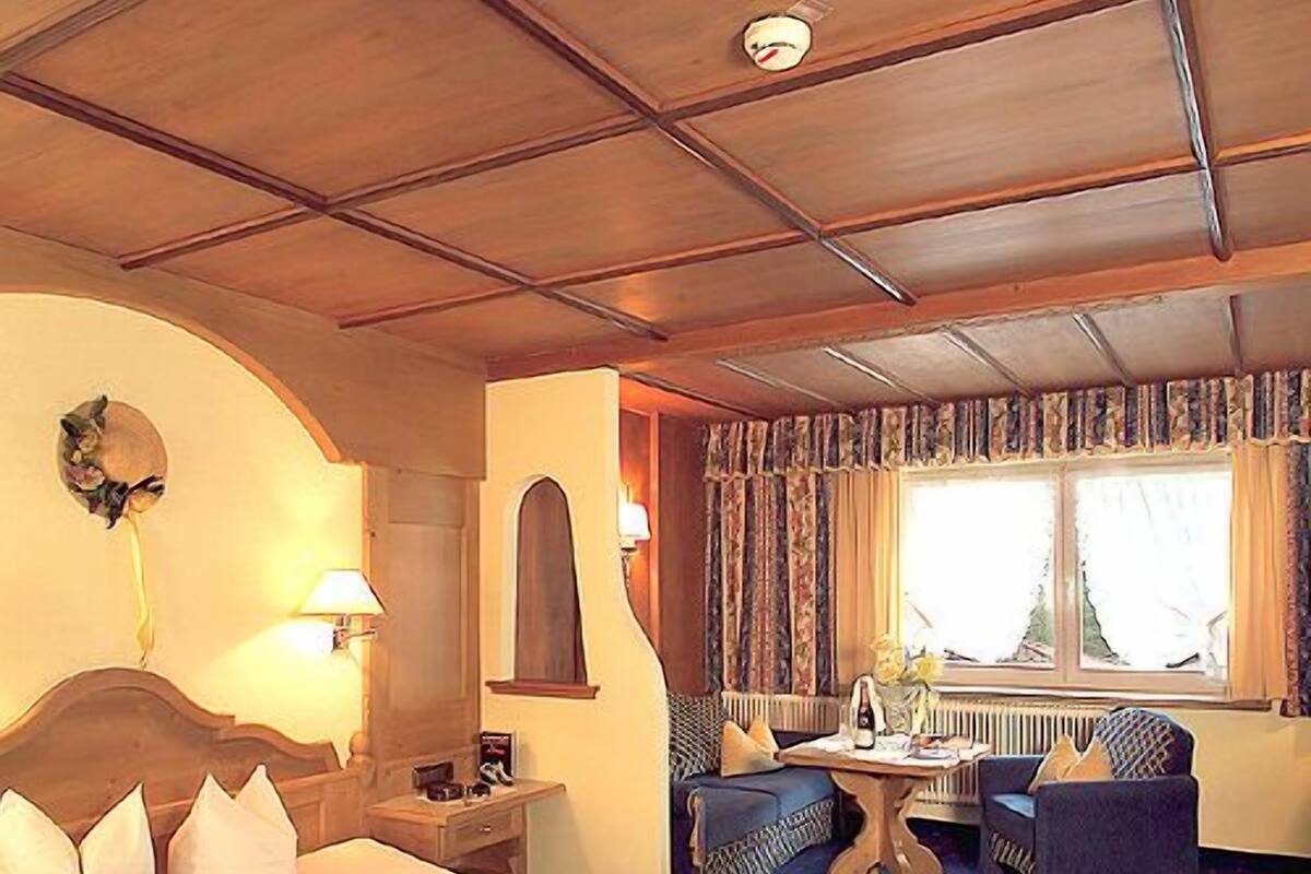 A hotel room with a bed, a desk, a chair, and a sofa.
