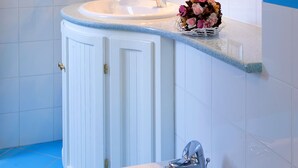 Un baño con tocador blanco, lavamanos, espejo y bañera.