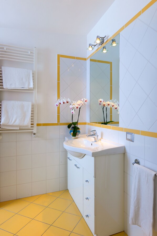 A bathroom with a white sink, a mirror, and a towel rack with white towels.