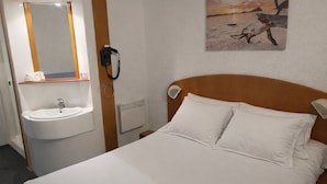 A hotel room with a bed, a white sink, and a mirror. - Quick Palace St Brieuc Tregueux (Tregueux)