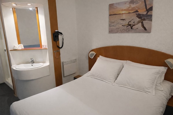 A hotel room with a bed, a white sink, and a mirror. - Quick Palace St Brieuc Tregueux (Tregueux)