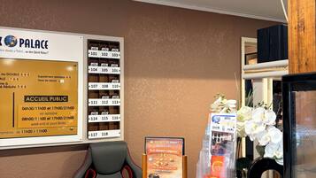 A reception desk with a sign listing room numbers and rates, a small display for a breakfast menu, and a refrigerator.